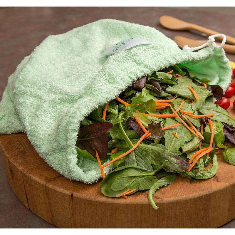 Light green super absorbent fabric lettuce storage bag with drawstring partially open on wooden cutting board, filled with mixed salad greens and shredded carrots, ideal for Kitchen & Food and Storage and Serving collections.