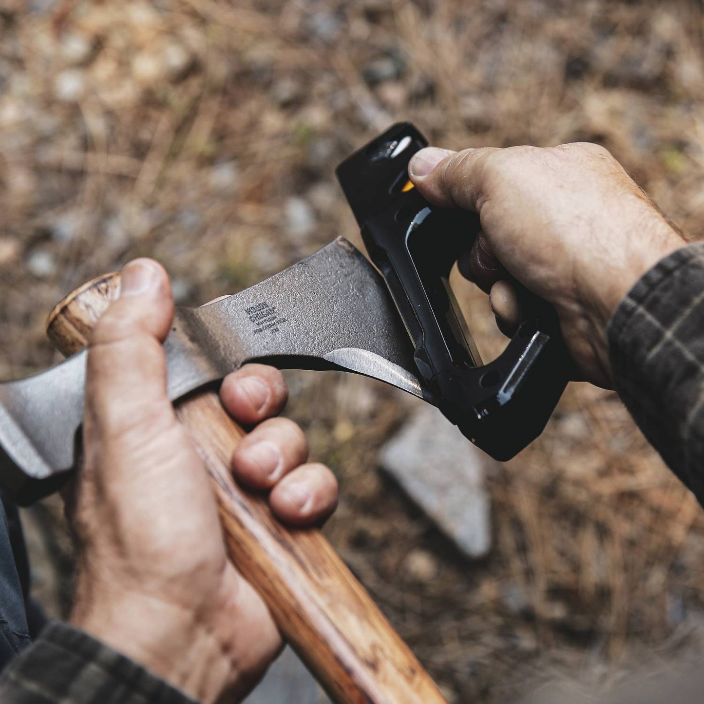 Handheld sharpener with ergonomic handle quickly refining the edge of a wooden-handled axe blade outdoors, suitable for Farm, Garden & Tool, Hand Tools and Hardware, and Sharpening collections.