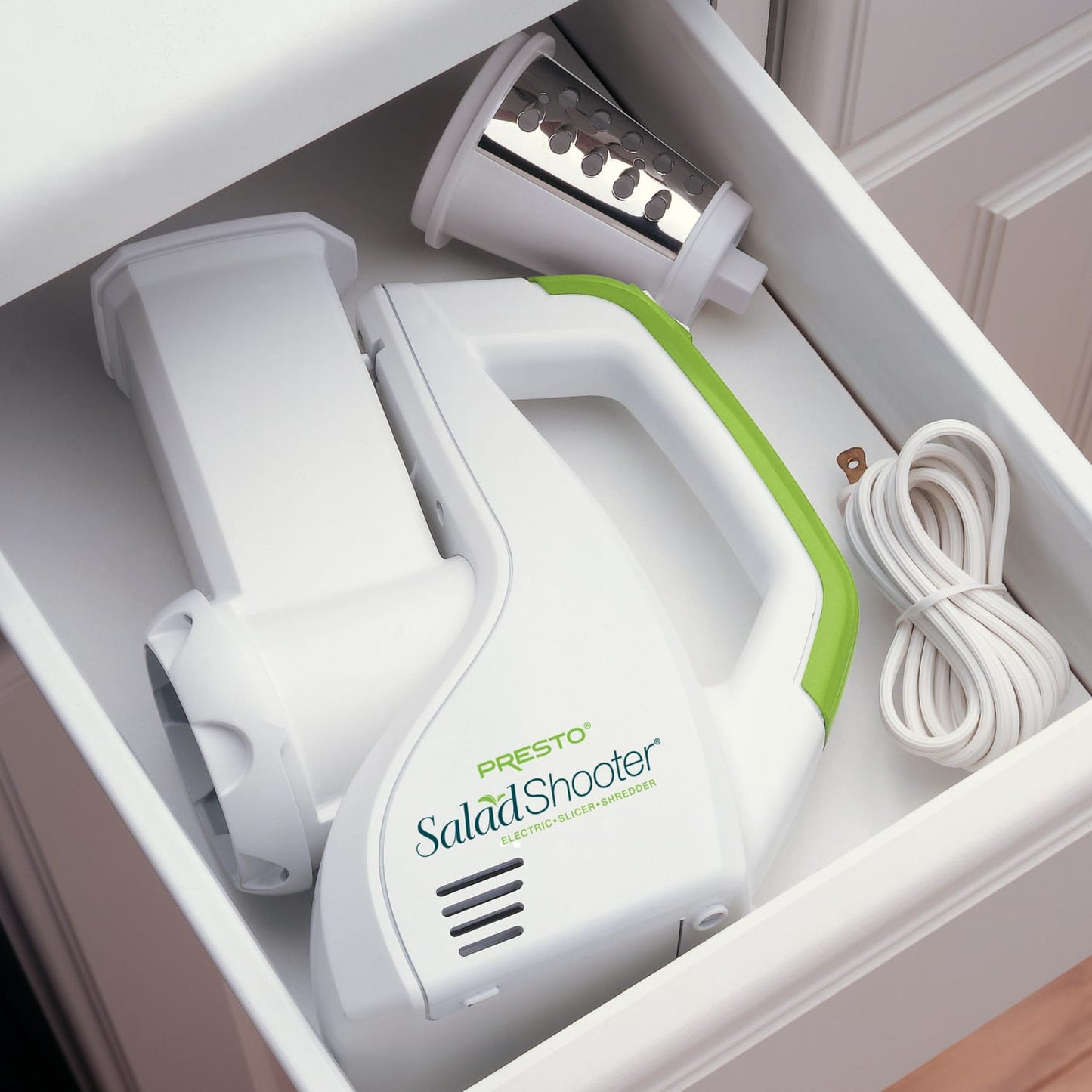 White and green electric slicer with detachable stainless steel shredding cone and power cord neatly stored in a kitchen drawer, ideal for Kitchen & Food and Food Prep collections