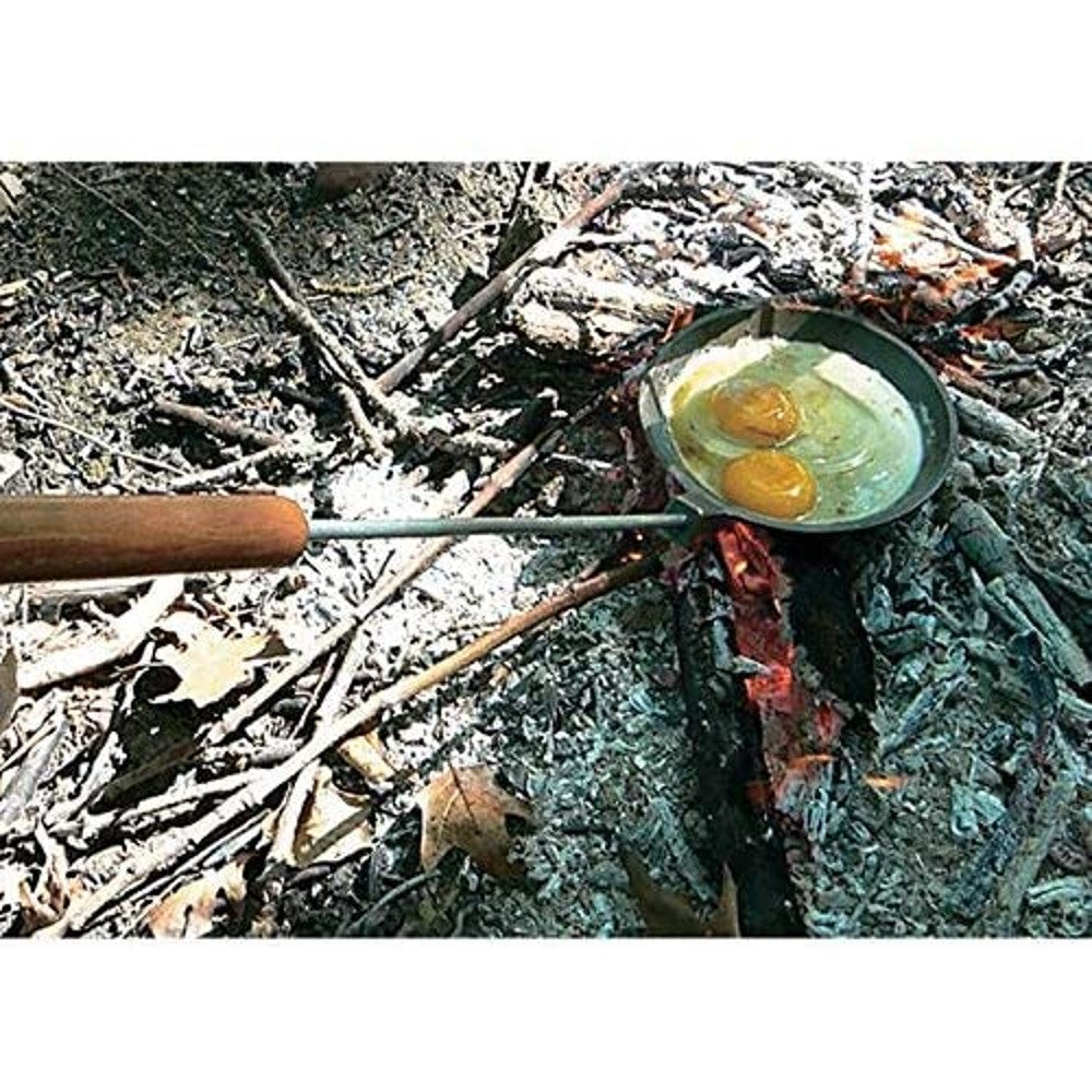 Cast iron skillet with a long wooden handle cooking two eggs over an open campfire, designed for safe outdoor use and featured in Farm, Garden & Tool, Camping, Best Sellers, and Promo Eligible collections.