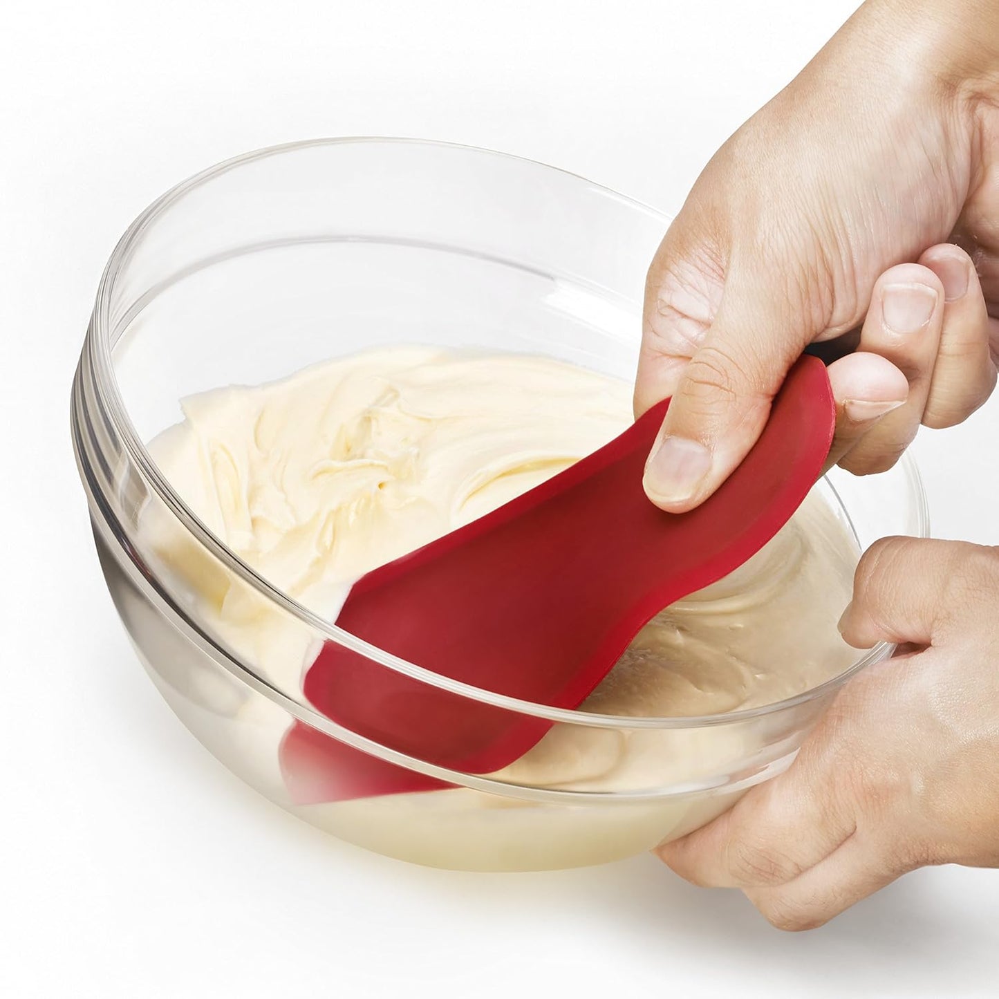 Red flexible silicone scraper with a thin metal core scraping batter from a clear glass bowl, designed for easy cleanup and smooth mixing in Kitchen & Food and Baking Supplies collections.