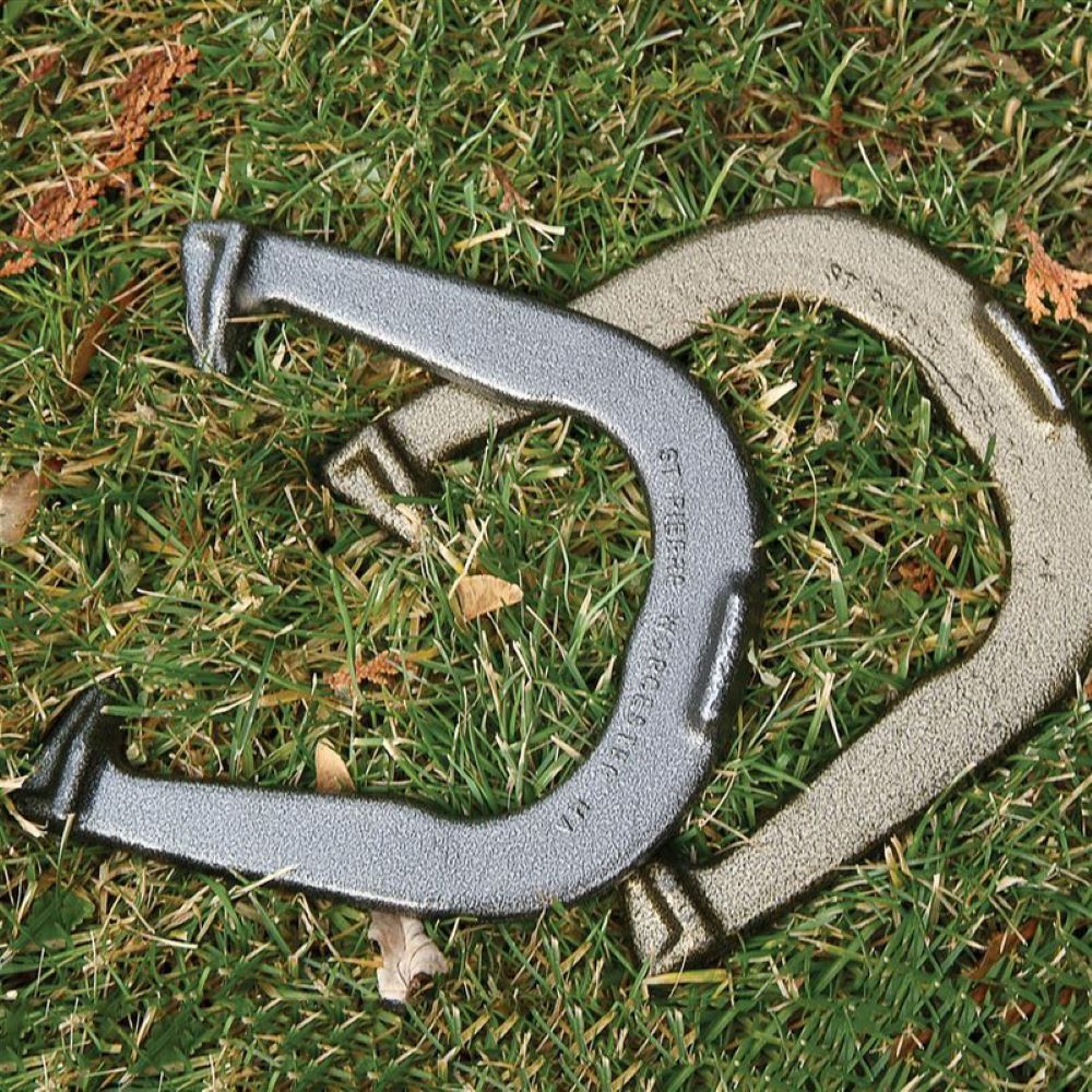 Two solid steel horseshoes, one silver and one gold-toned, laid on grass representing a premium, durable set made in USA, featured in lawn games and best sellers collections.