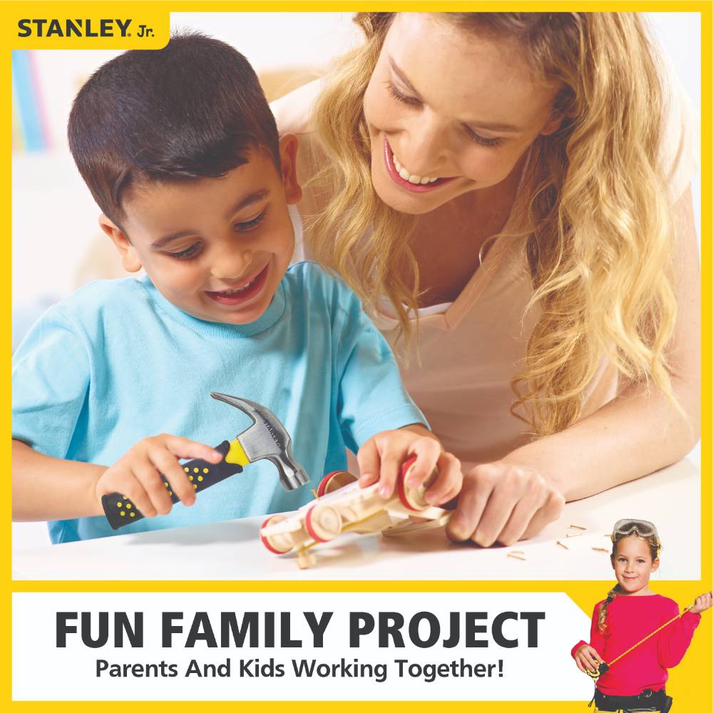 Smiling young boy using a child-sized hammer to work on a wooden project with his mother, promoting family bonding and indoor play with real hand tools.