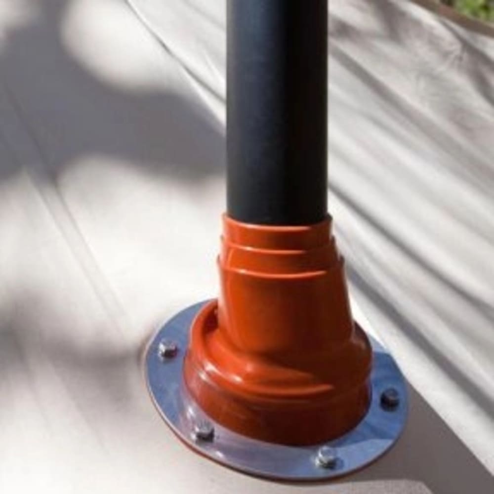 Close-up of a black pipe secured with an orange mounting flange attached to a beige tent fabric, designed for safe installation in camping and outdoor gear collections.