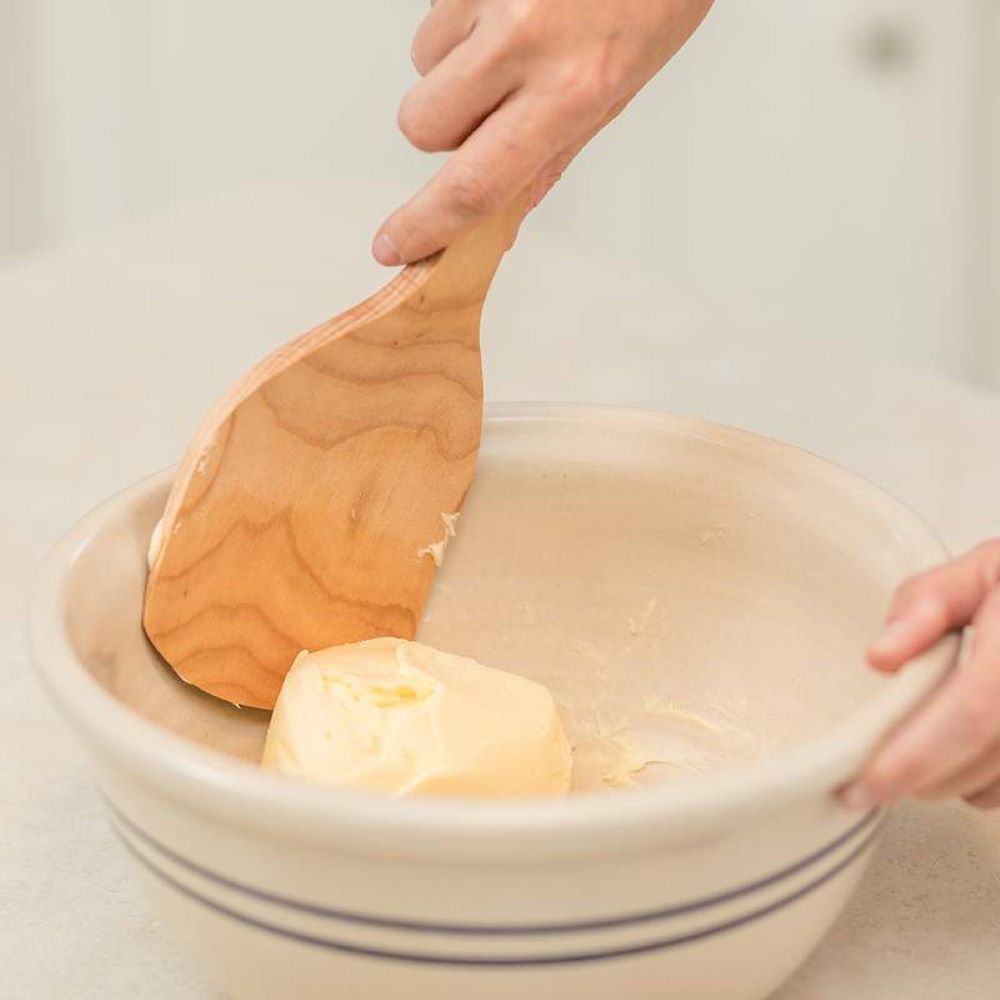 Handcrafted American hard maple paddle with a curved, extra-wide design for easier butter handling, shown pressing homemade butter in a ceramic mixing bowl, ideal for Kitchen & Food and Specialty Equipment collections.