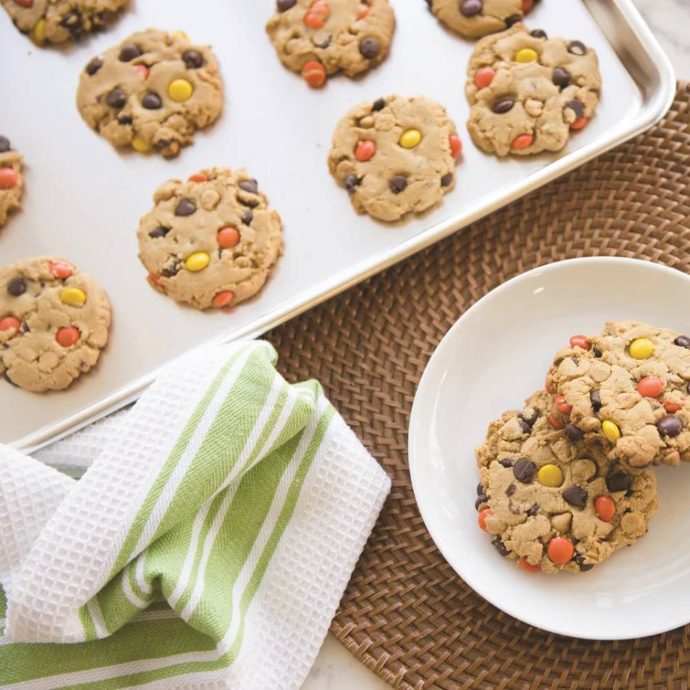 Aluminum half sheet baking pan with lid featuring freshly baked peanut butter cookies with colorful candy pieces, paired with a green-striped kitchen towel and white plate, ideal for Kitchen & Food, Cookware, and Baking Supplies collections.