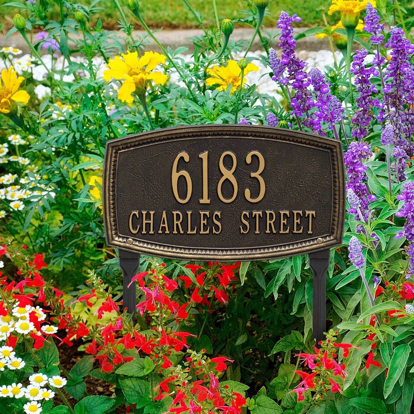 Black custom lawn plaque with raised border displaying address number and street name, set among colorful garden flowers, crafted in USA for Home & Decor and Mailboxes collections.