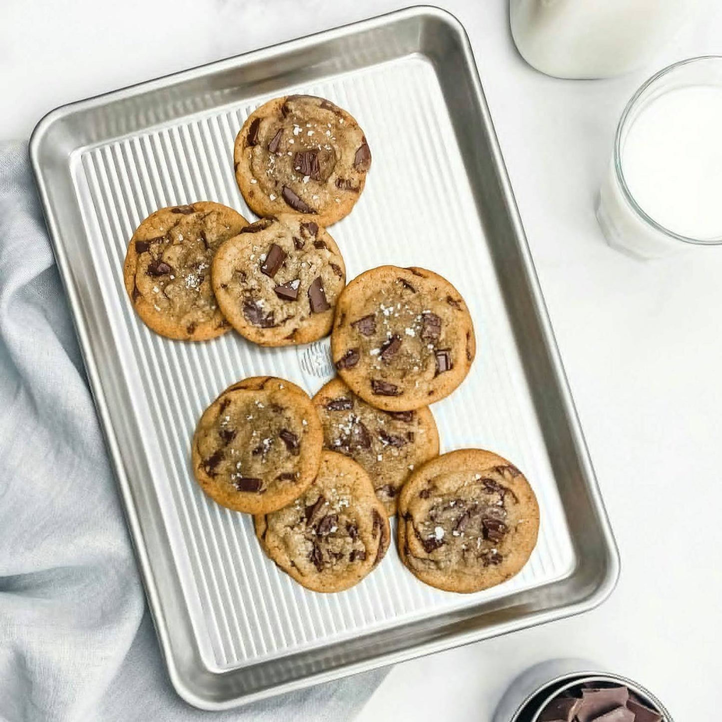 Aluminized steel quarter sheet pan holding freshly baked chocolate chunk cookies sprinkled with sea salt, presented with milk and baking ingredients, ideal for Kitchen & Food, Cookware, Baking Supplies, Pots and Pans, USA Made, Best Sellers, and Promo Eligible collections.