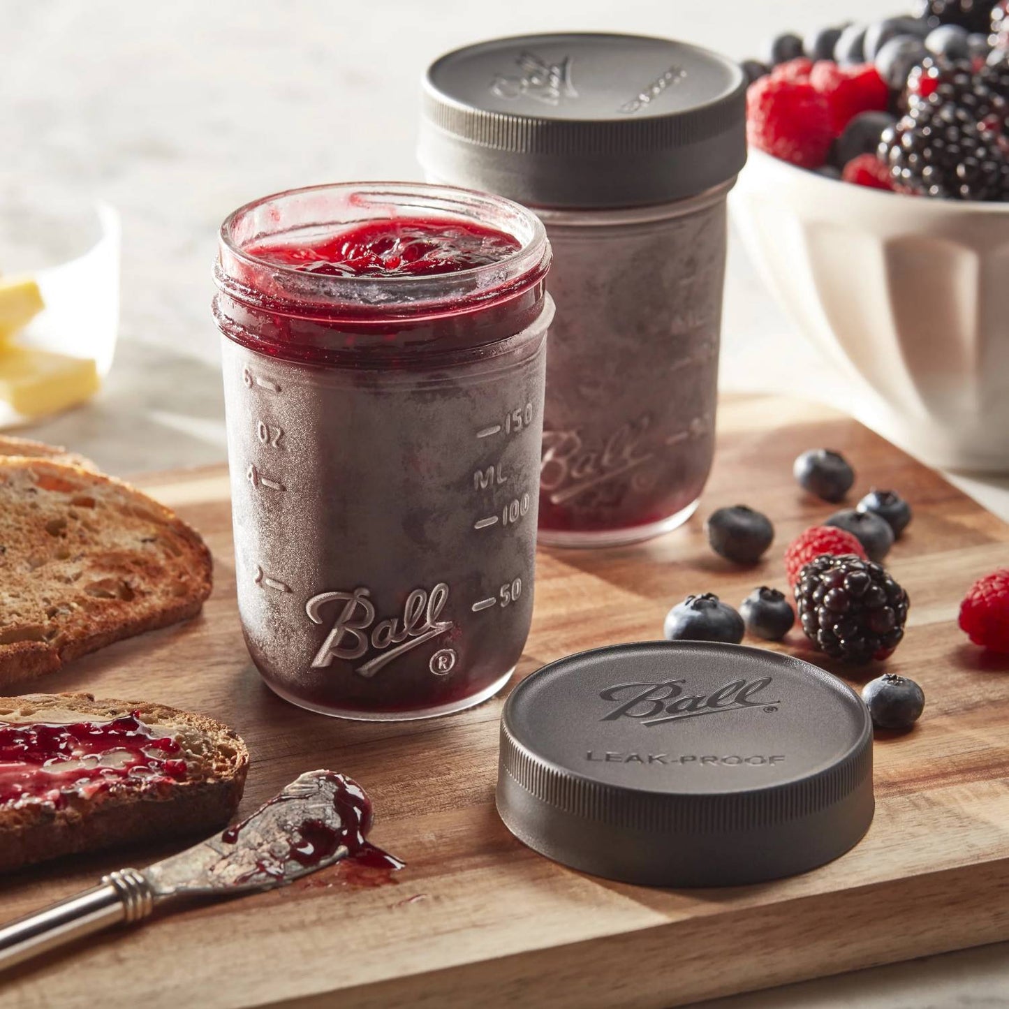 Clear regular mouth jars filled with berry jam and sealed with matte black leak-proof lids, displayed on a wooden board with fresh berries and toasted bread, ideal for Kitchen & Food, Storage and Serving, Best Sellers, Promo Eligible collections.