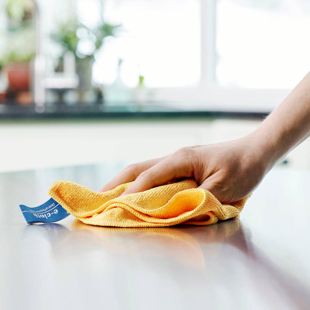 Hand holding a yellow microfiber cleaning cloth with thick fibers wiping a smooth countertop, ideal for chemical-free cleaning in Home & Decor and Household Cleaning collections.