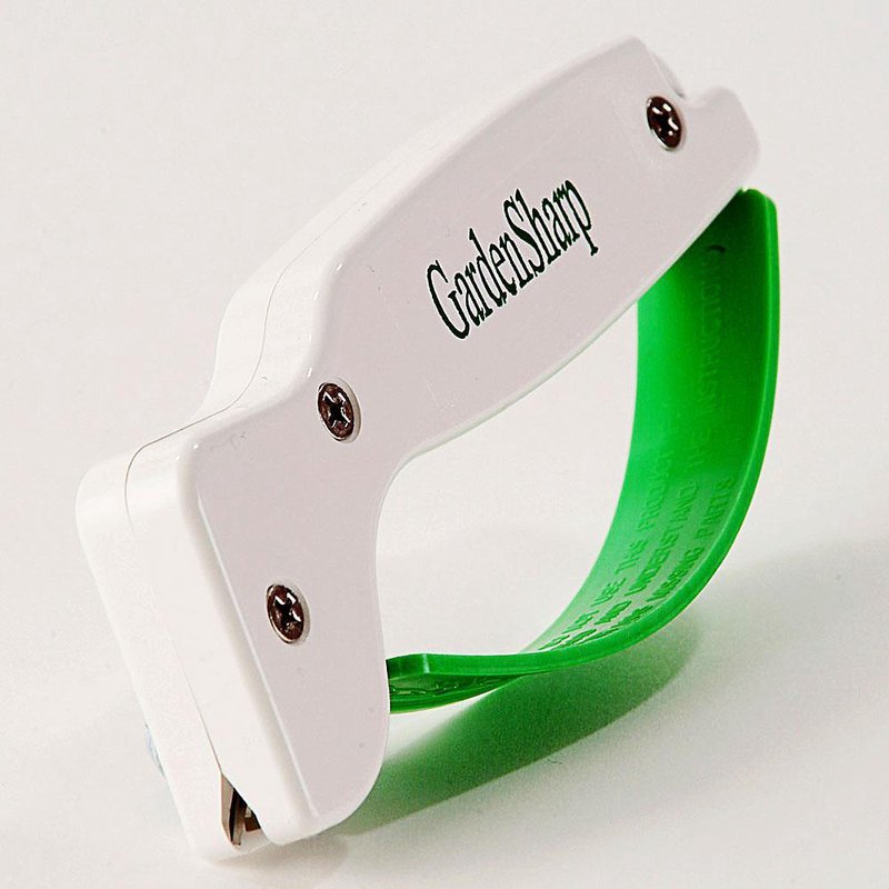 Compact handheld garden tool sharpener with a white body and green handle, featuring a reversible diamond-honed tungsten carbide edge, made in USA for farm, garden, and lawncare use.