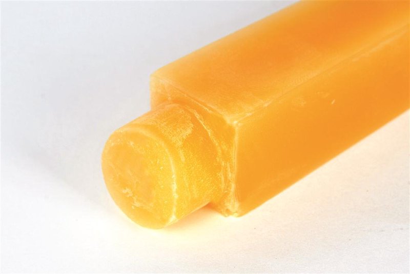 Close-up of a handcrafted 100 percent beeswax square taper candle in warm honey color, featuring a cylindrical base and long burn time, made in USA for lamps and lighting collections.
