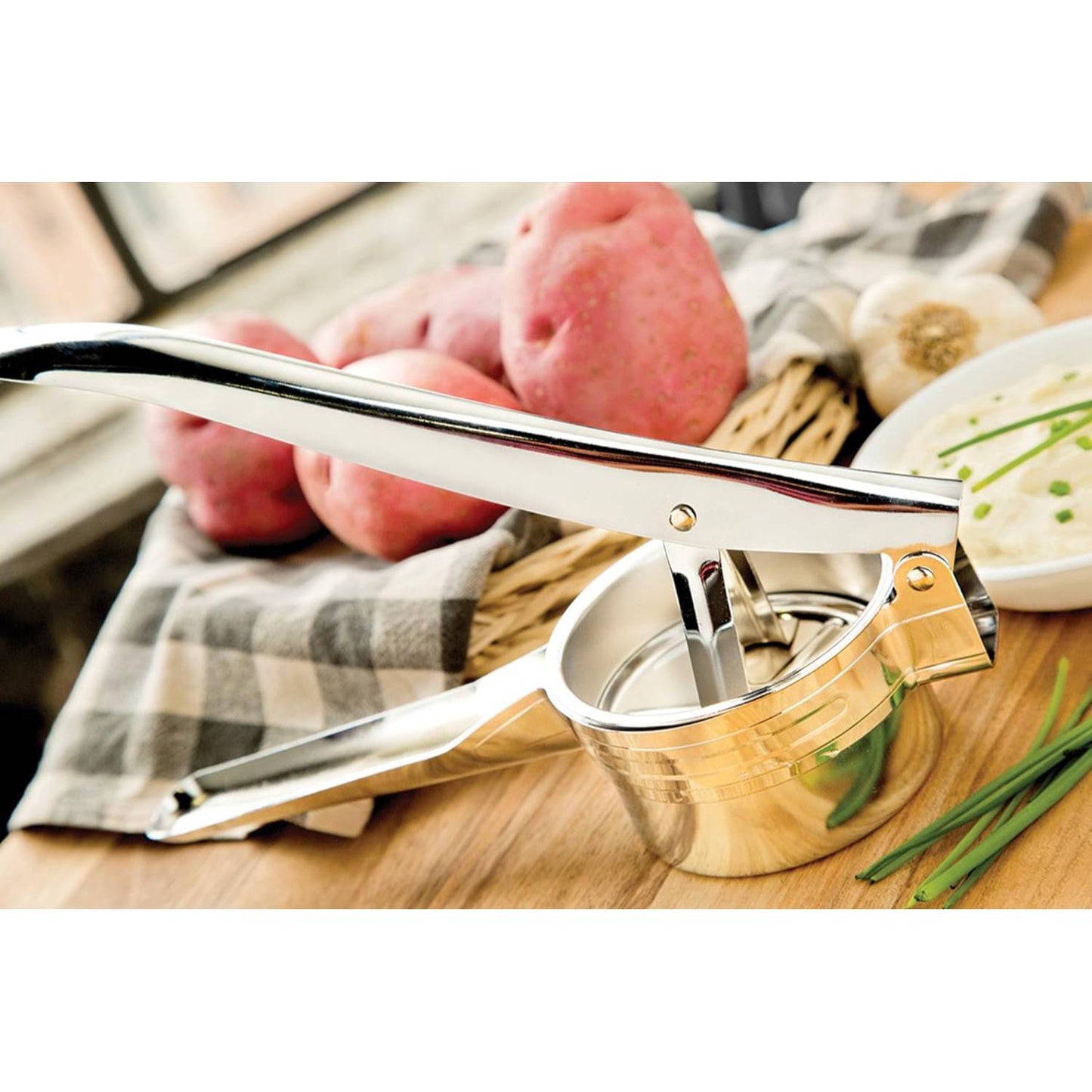 Polished metal potato ricer and fruit press with ergonomic handles, designed to simplify food prep, displayed with fresh potatoes, herbs, and kitchen linens, ideal for Kitchen & Food, Kitchen Gadgets, Cooking and Baking Helpers, Best Sellers, and Promo Eligible collections.