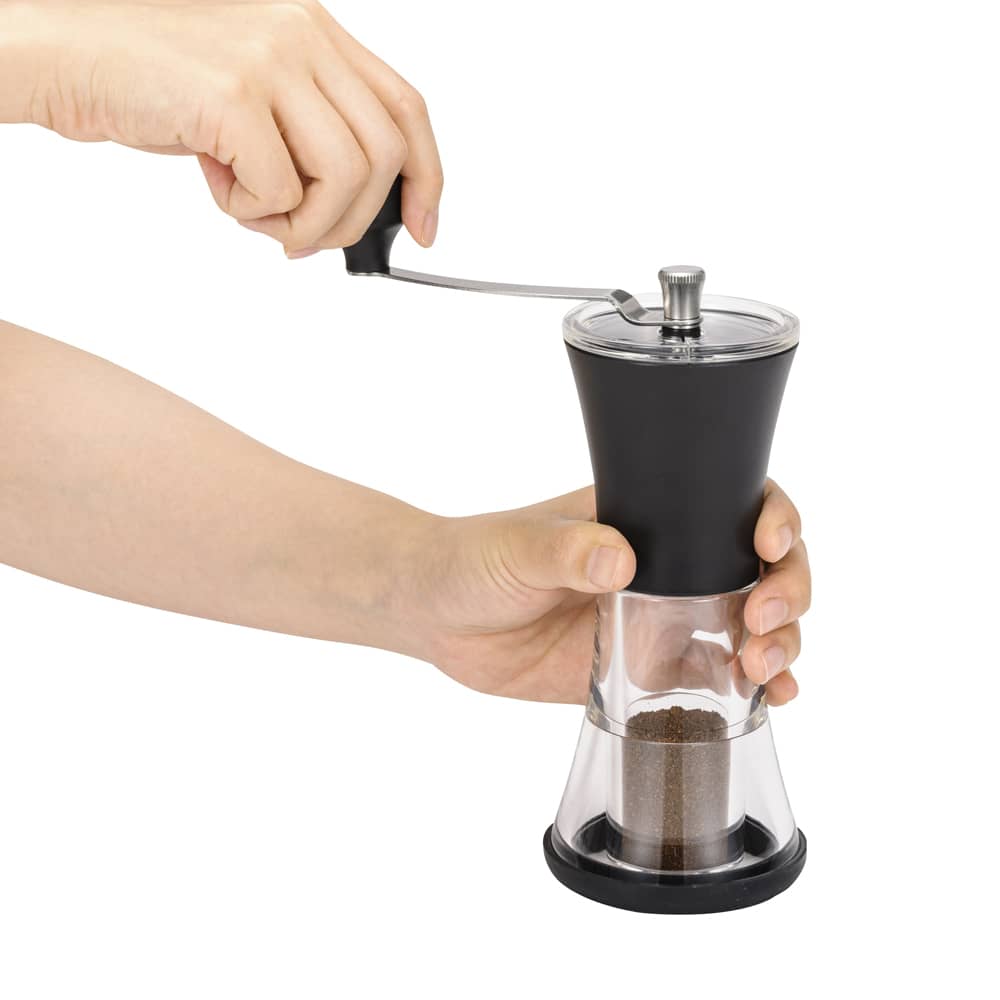 Hands holding and turning a slim adjustable coffee grinder with a ceramic mechanism, featured in Kitchen & Food, Brewing Coffee and Tea, and Kitchen Gadgets collections.