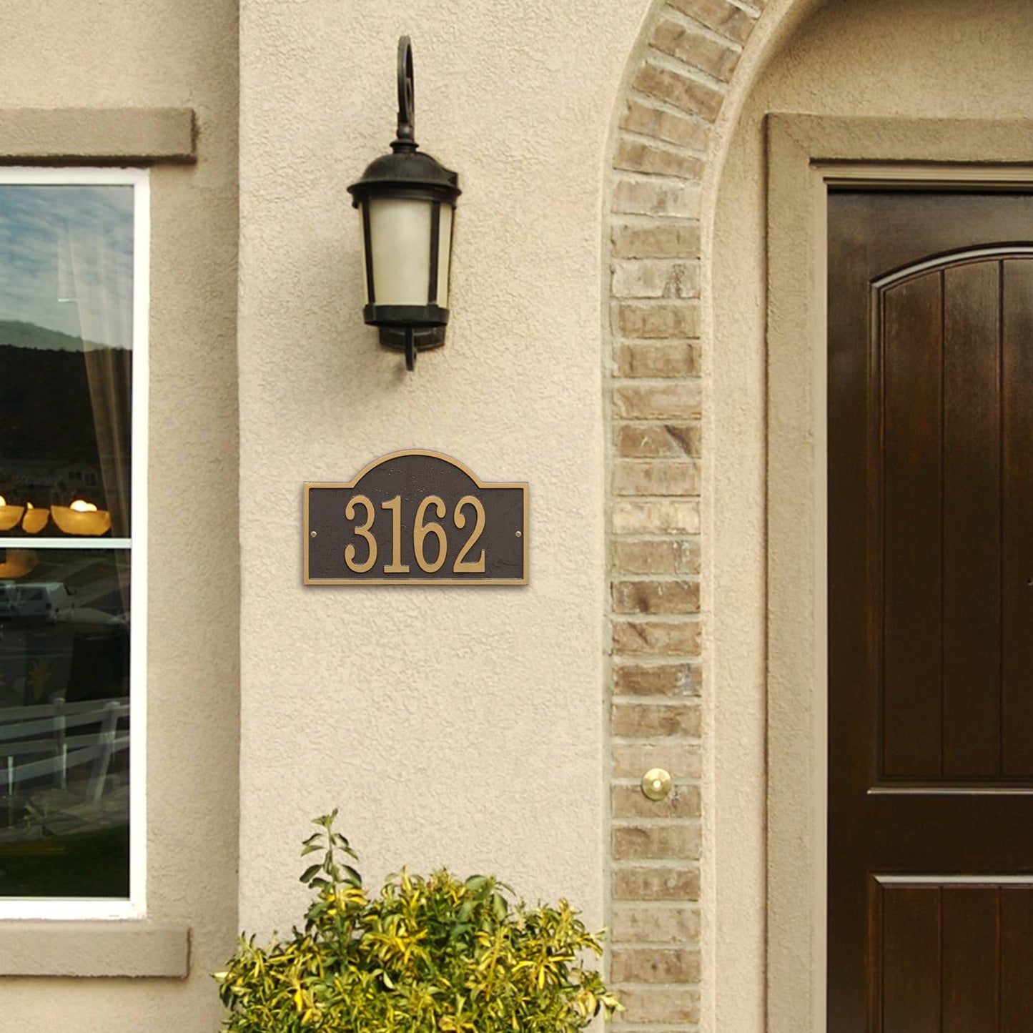 Custom bronze and gold arched rectangle address plaque with raised numbers mounted on beige stucco wall beneath black outdoor lantern, enhancing curb appeal in Home & Decor and USA Made collections.