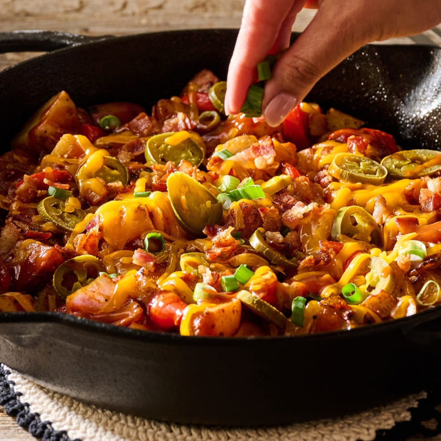 Close-up of a skillet filled with hearty ranch-style casserole topped with melted cheddar, jalapeño slices, bacon bits, and fresh green onion garnish, showcasing rustic Western flavors from a bestselling cookbook collection.