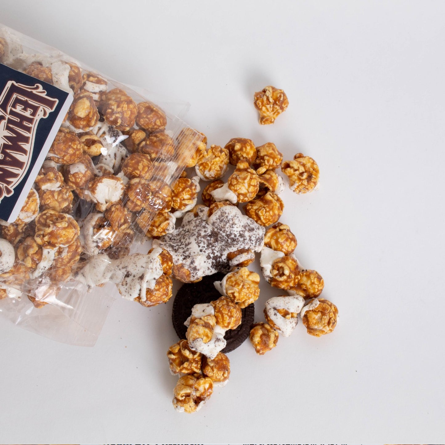 Clear bag of handcrafted caramel popcorn crunch with chocolate cookie pieces and white drizzle, a unique sweet and crunchy snack made in USA, ideal for Kitchen & Food, Snacks and Sweets, Popcorn, USA Made, Best Sellers, and Promo Eligible collections.