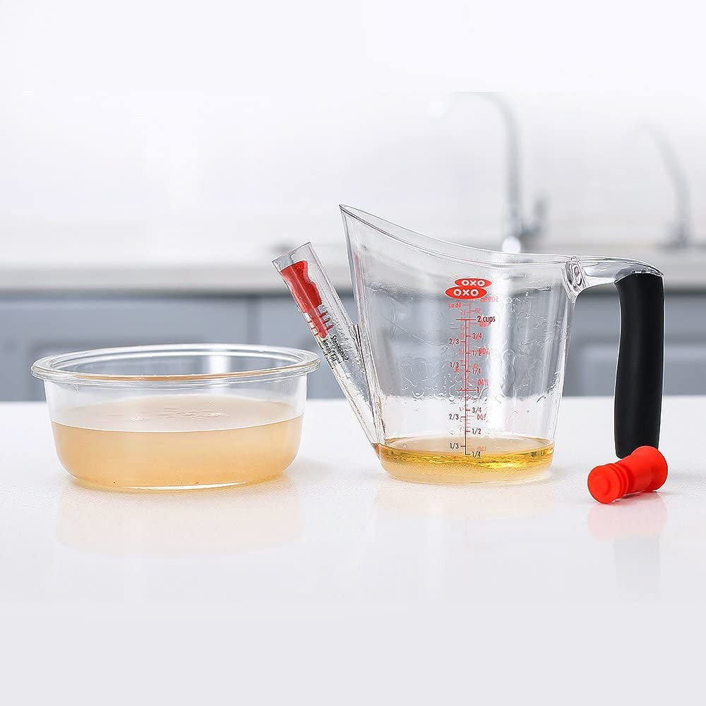 Clear plastic fat separator with black cushioned grip handle and red stopper, featuring measurement markings and built-in strainer, ideal for Kitchen & Food, Kitchen Gadgets, Cooking and Baking Helpers, Best Sellers, and Promo Eligible collections.