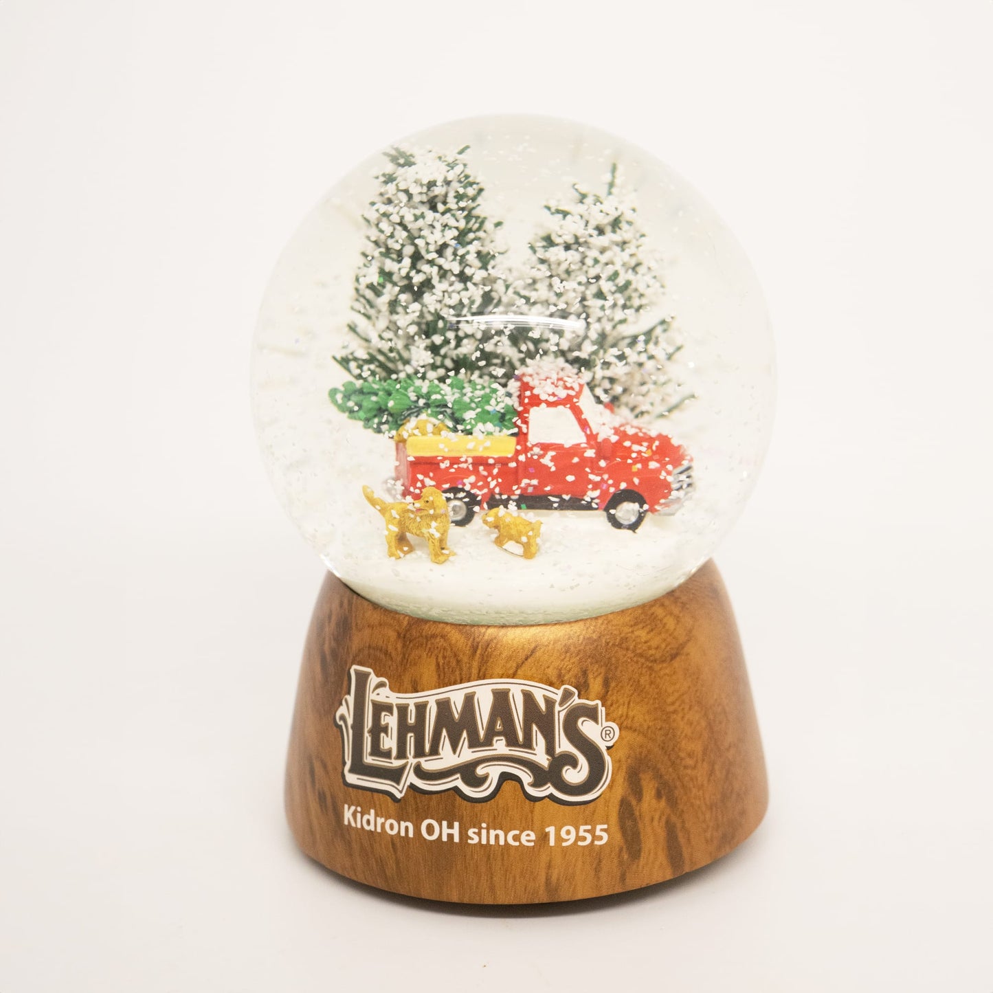 Handcrafted musical snow globe with a red truck carrying a Christmas tree and two dogs in a snowy pine forest, featuring a wooden base, ideal for Home & Decor and Holiday Decor collections.