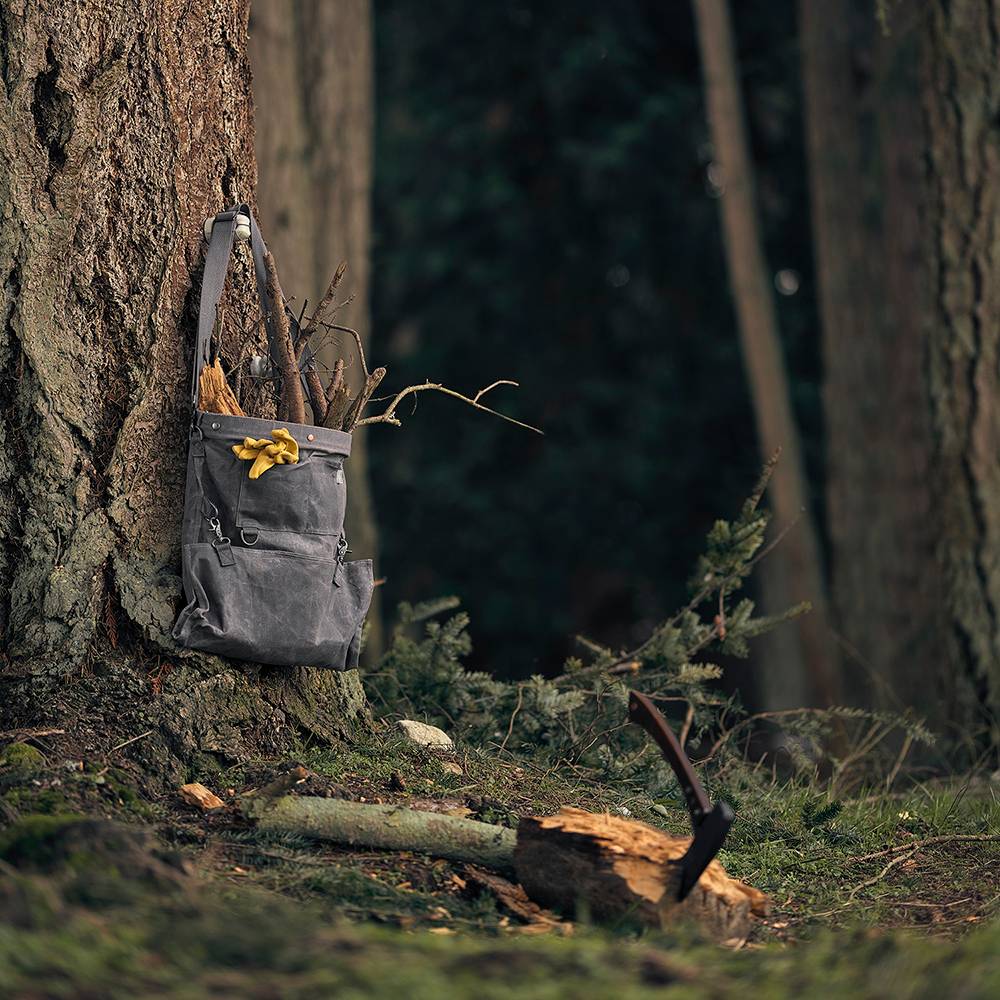 Weather- and water-resistant charcoal gray harvesting bag with convertible straps and removable watertight liner, hanging on a tree in a forest setting, ideal for Farm, Garden & Tool and Apple Harvest Supplies collections.