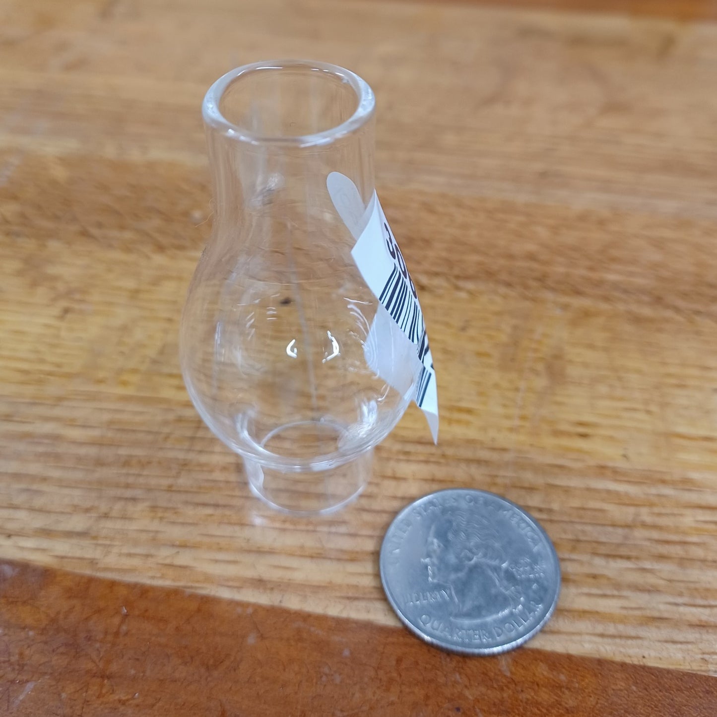 Clear handcrafted glass oil lamp chimney with 3/4" base, shown next to a quarter for scale, suitable for lamps and lighting, parts and accessories, and chimneys and globes collections.