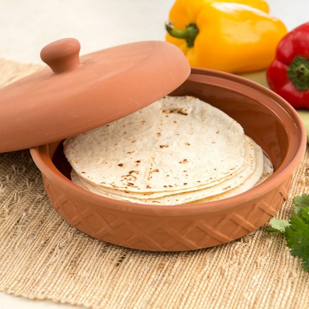 Handcrafted terra cotta tortilla warmer with textured exterior and glazed interior, holding warm tortillas, set on woven placemat with fresh yellow and red bell peppers, part of Kitchen & Food, Storage and Serving, Best Sellers, and Promo Eligible collections.