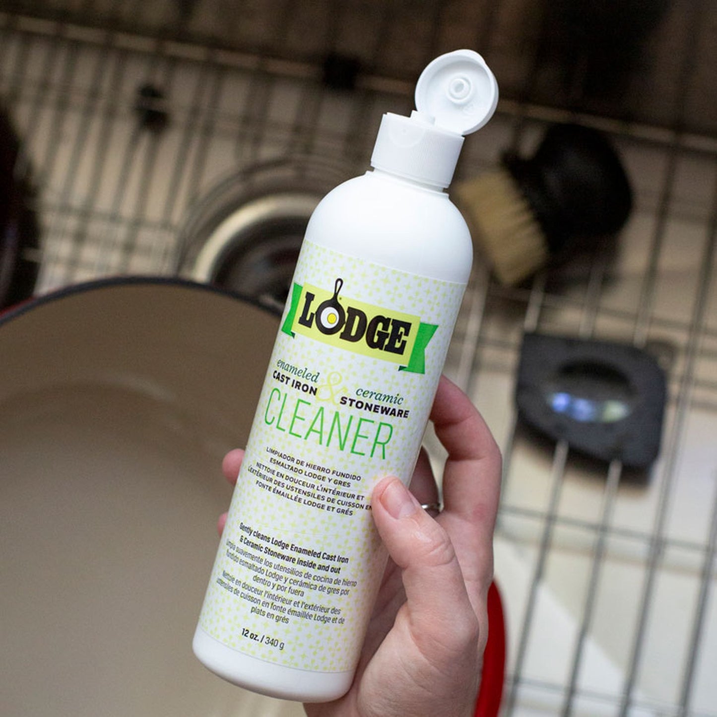Hand holding a white bottle of biodegradable cleaner designed for enameled cast iron and ceramic stoneware, featured in Kitchen & Food, Cookware, Cast Iron, and Best Sellers collections.