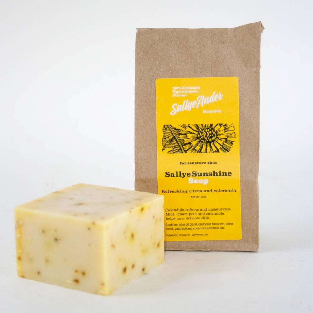 Handcrafted hypoallergenic soap bar with creamy yellow tone and visible calendula flecks, paired with kraft paper packaging featuring bright yellow label, made in USA, ideal for Health & Wellness, Grooming and Personal Hygiene, Soaps, and USA Made collections.