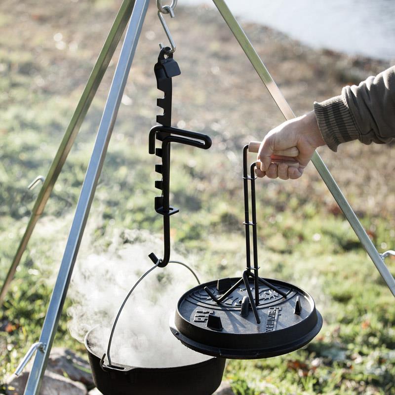 Black coated steel adjustable trammel hook with notched height settings suspending a steaming cast iron pot and lid from a tripod, perfect for Farm, Garden & Tool and Camping use.
