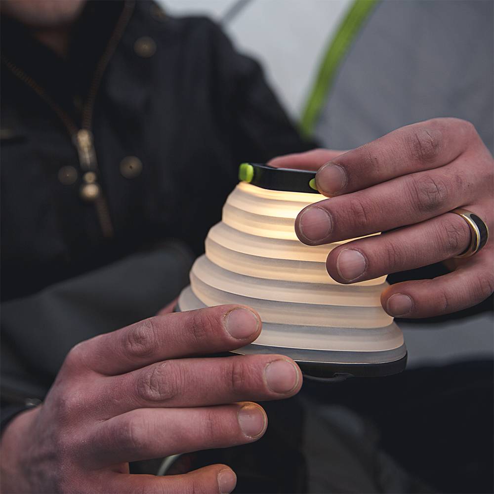 Hands holding a lightweight, collapsible solar lantern emitting soft light, designed for outdoor use and featured in lamps, emergency supplies, and solar LED collections.