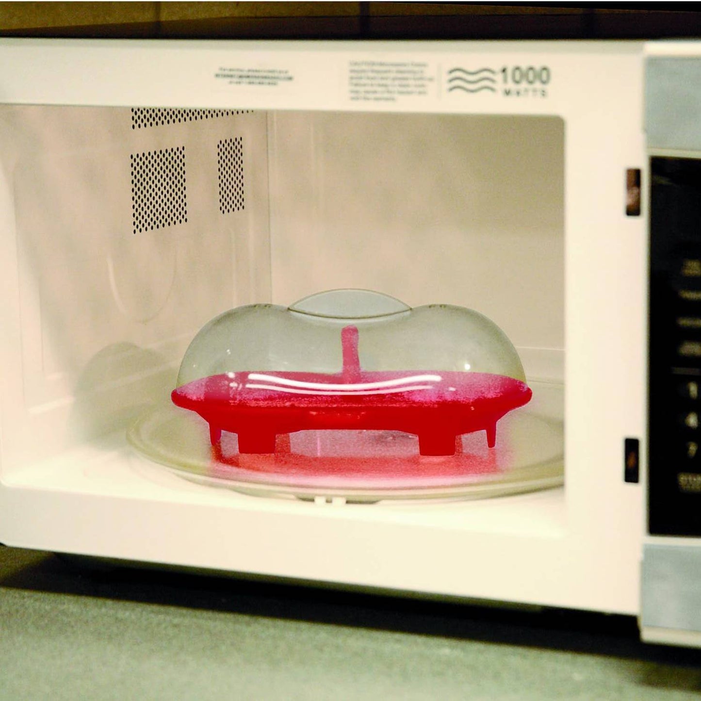 Red silicone double egg poacher with clear vented lid inside microwave, designed for quick and easy poaching, ideal for Kitchen & Food and Cooking and Baking Helpers collections.