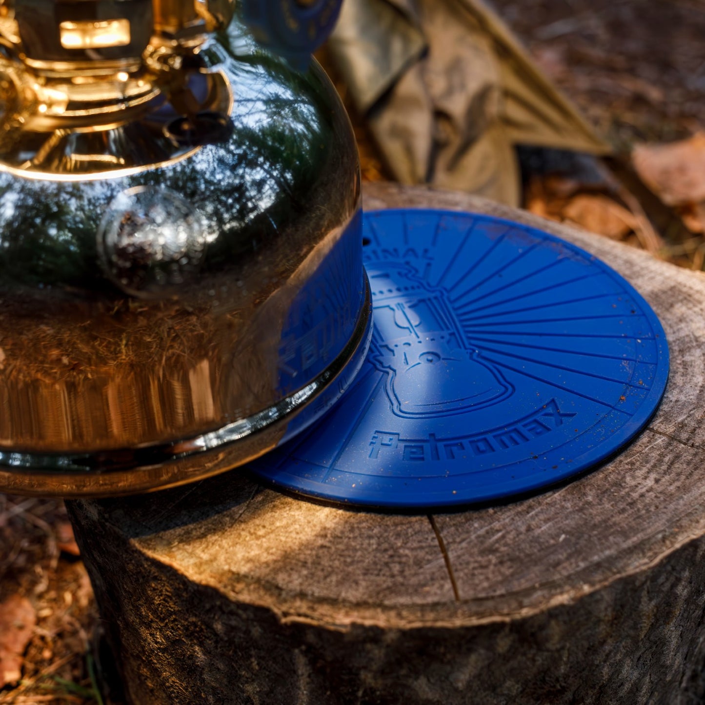 Round blue silicone heat-resistant coaster with raised lamp design and Petromax branding, featuring a non-slip surface and hanging eyelet, ideal for camping and lamps & lighting collections.