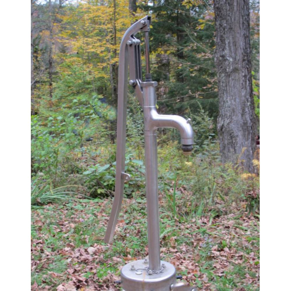 Handcrafted stainless steel deep well pump head mounted outdoors in a natural wooded setting, highlighting a durable and reliable water pump solution from USA Made collections.
