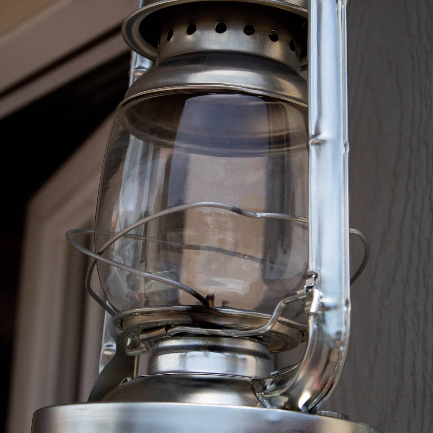 Close-up of a clear replacement glass globe installed on a traditional metal lantern, ideal for use in lamps & lighting, camping, emergency supplies, and outdoor settings.