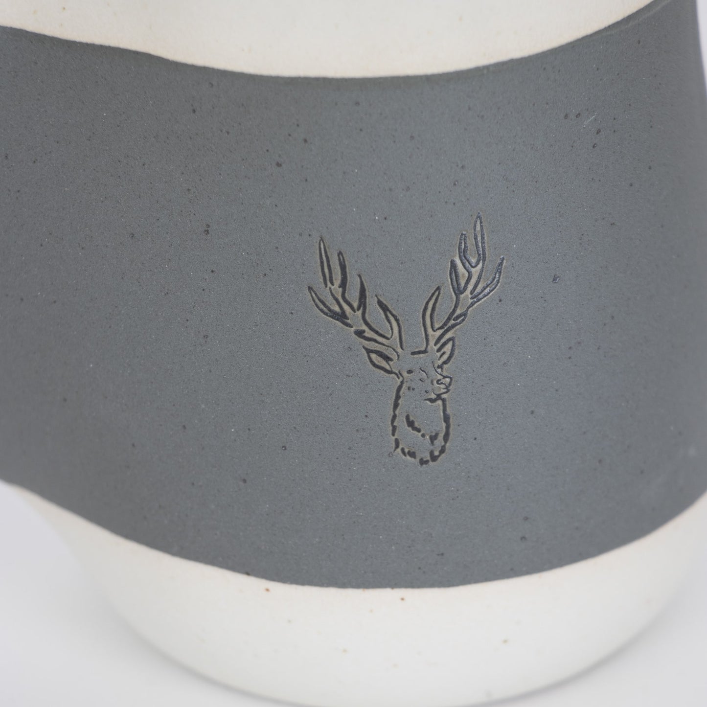 Handcrafted gray ceramic mug with a white base and embossed stag design on the front, featuring a cozy handwarmer pocket, ideal for Kitchen & Food, Dinnerware, and Best Sellers collections.