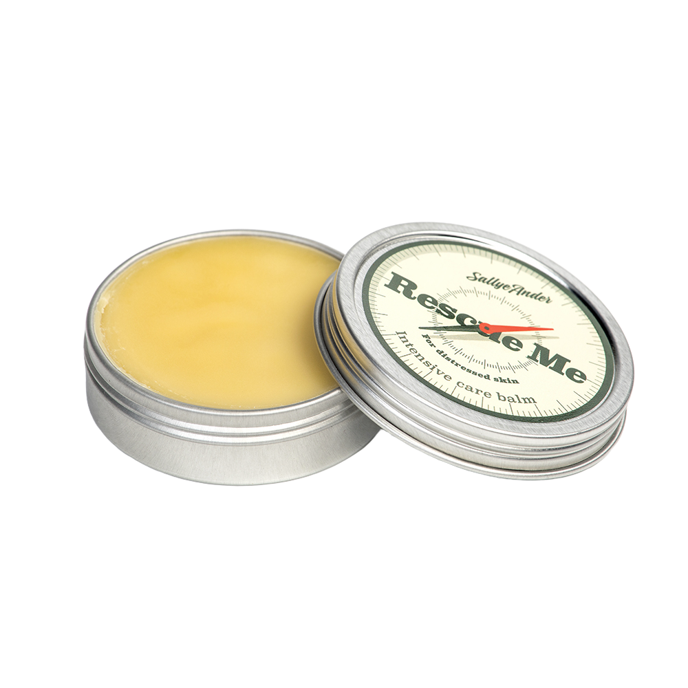 Open metal tin of handcrafted balm with pale yellow ointment inside and a cream-colored lid labeled in green and red, ideal for Health & Wellness and USA Made collections.