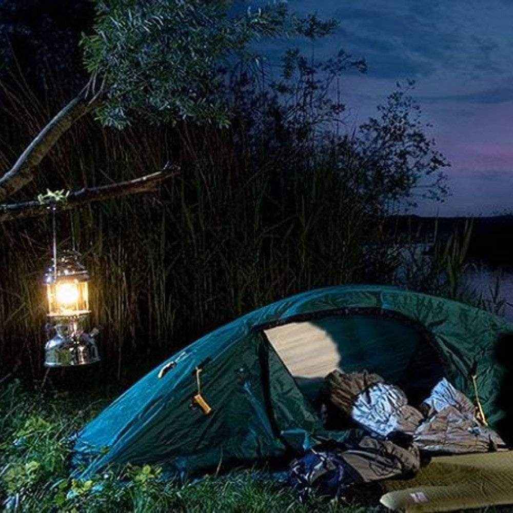 Outdoor camping scene at twilight featuring a glowing pressure lamp hanging from a tree branch beside a pitched green tent, evoking warmth and reliable illumination in Lamps & Lighting, Parts and Accessories, Other Parts, Best Sellers, and Promo Eligible collections.