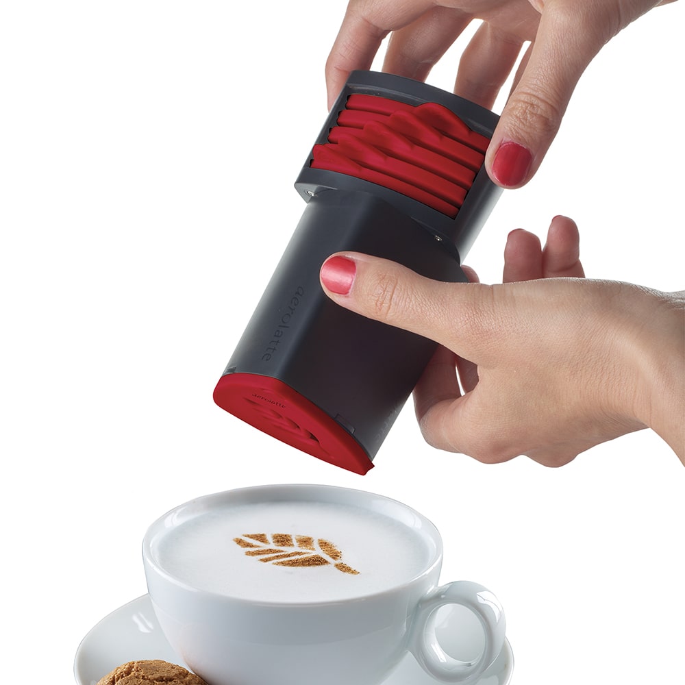 Handheld coffee stencil tool with six interchangeable red pattern discs being pressed over a cappuccino cup to create a leaf design, featured in Kitchen & Food, Brewing Coffee and Tea, and Kitchen Gadgets collections.