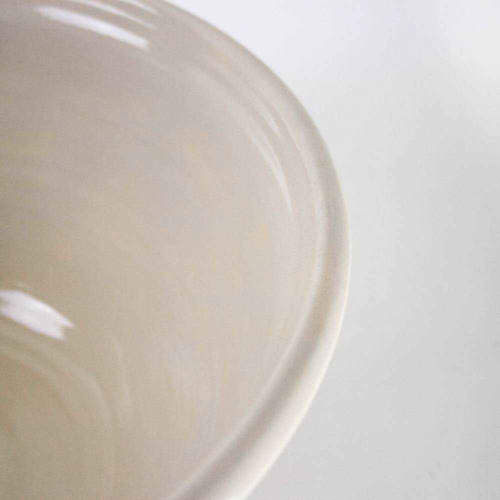 Close-up of a handcrafted cream stoneware mixing bowl with subtle blue stripes, made in USA, ideal for Kitchen & Food, Cookware, Baking Supplies, and Storage collections.
