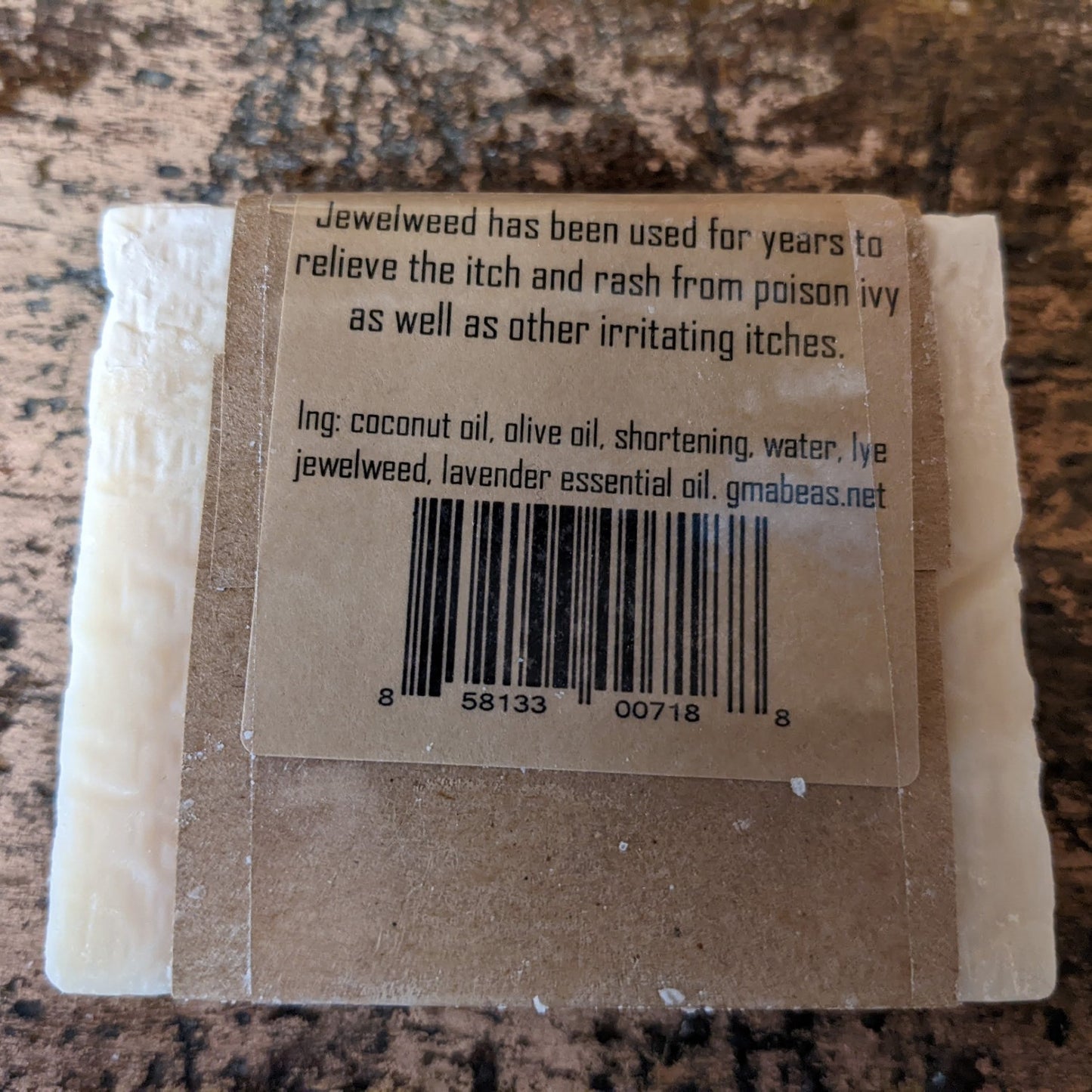 Handcrafted soap bar wrapped in natural brown paper packaging, listing ingredients like jewelweed and lavender essential oil, promoting health and wellness in USA made collections.