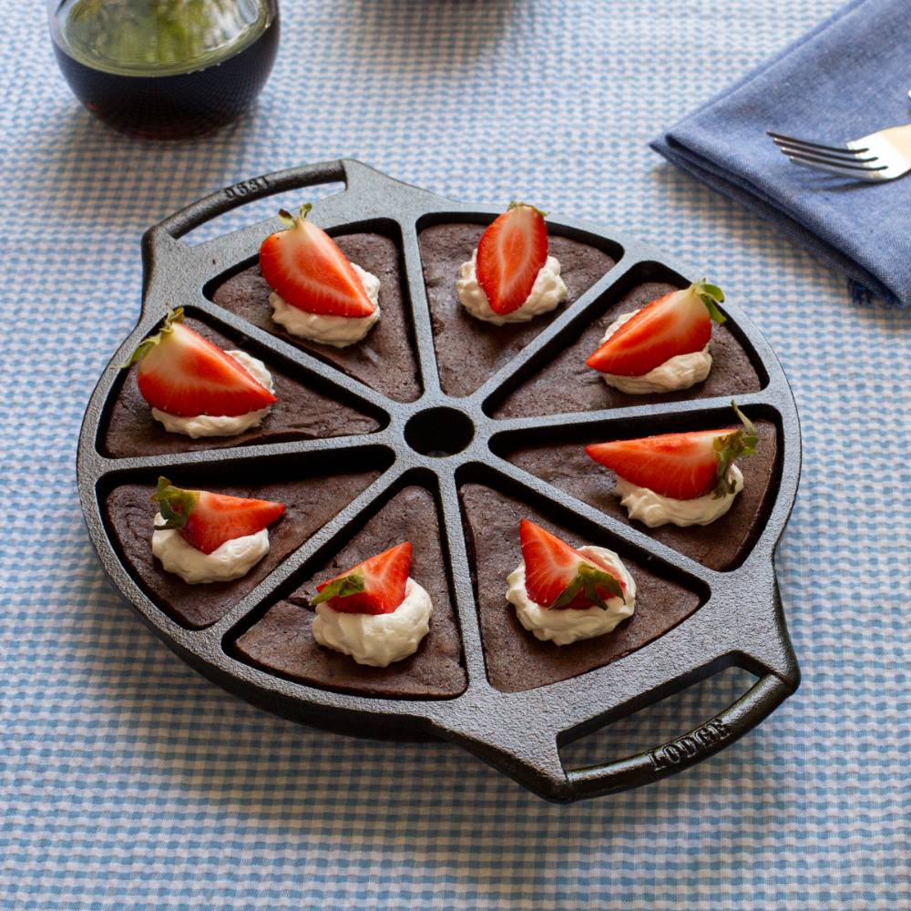 Cast iron wedge pan with eight sections, naturally seasoned with vegetable oil, featuring a dual handle design, presented with chocolate wedges topped with whipped cream and fresh strawberries, ideal for Kitchen & Food, Cookware, Cast Iron, USA Made, Best Sellers, and Promo Eligible collections.
