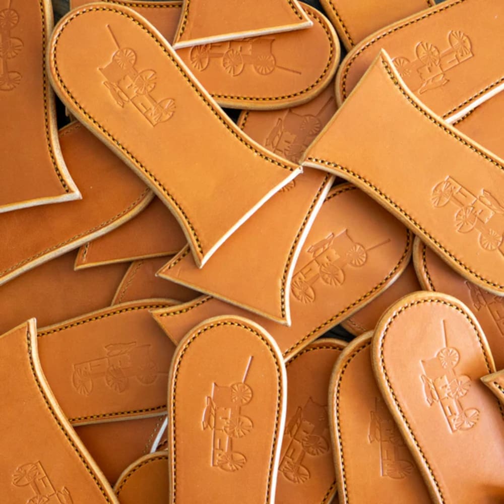 Collection of handcrafted vegetable-tanned leather skillet handle covers embossed with a vintage wagon design, heat-resistant and made in USA, perfect for kitchen and cast iron cookware.