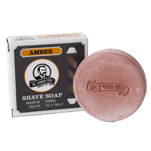 Amber-colored shaving soap puck with embossed branding alongside its box featuring vintage design, containing avocado oil and vitamin E, ideal for Health & Wellness and Grooming collections.
