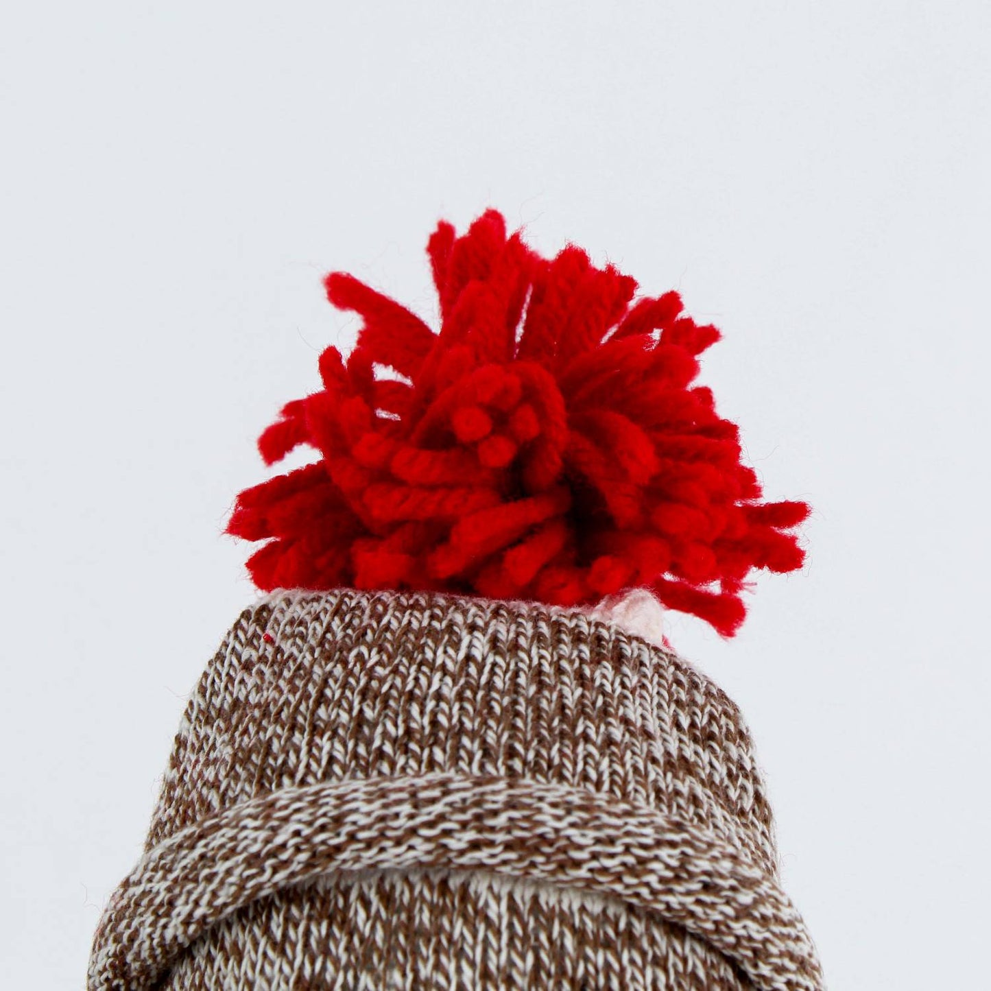 Close-up of a hand-sewn sock monkey wearing a thick knit hat topped with a bright red pom-pom, handcrafted in the USA and featured in Toys, Books & Games, Children's Toys, and Best Sellers collections.