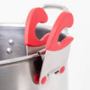 Close-up of a pot clip spoon holder with red silicone grips clamped securely onto a stainless steel pot, designed to keep utensils within reach and off kitchen surfaces in Kitchen & Food and Kitchen Gadgets collections.