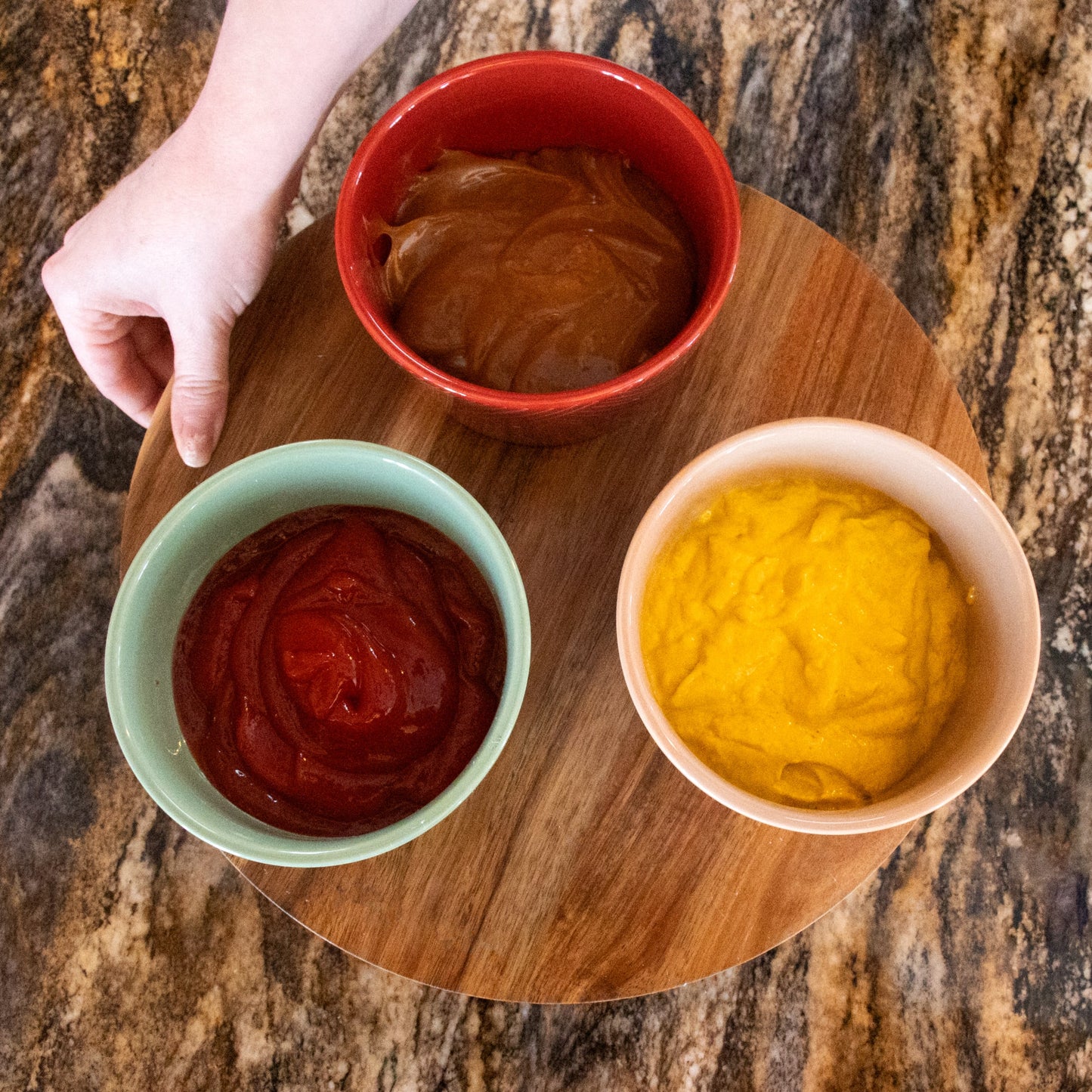 Handcrafted 12-inch wooden Lazy Susan turntable with three ceramic condiment bowls in red, green, and beige filled with sauces, ideal for Kitchen & Food, Storage and Serving collections.