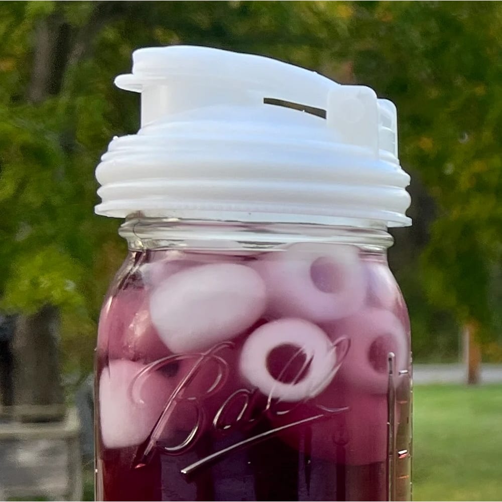 Clear regular-mouth glass jar filled with purple iced beverage, topped with a white no-break plastic pour lid featuring a flip-top spout and carry loop, made in USA, suitable for Kitchen & Food, Dinnerware, Kitchen Gadgets, Kitchen Accessories, USA Made, Best Sellers, and Promo Eligible collections.