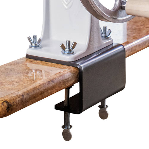 Heavy-duty steel clamp securely attaching a grain mill to a polished wooden countertop, designed for kitchen use in Grain Mills, USA Made, and Best Sellers collections.