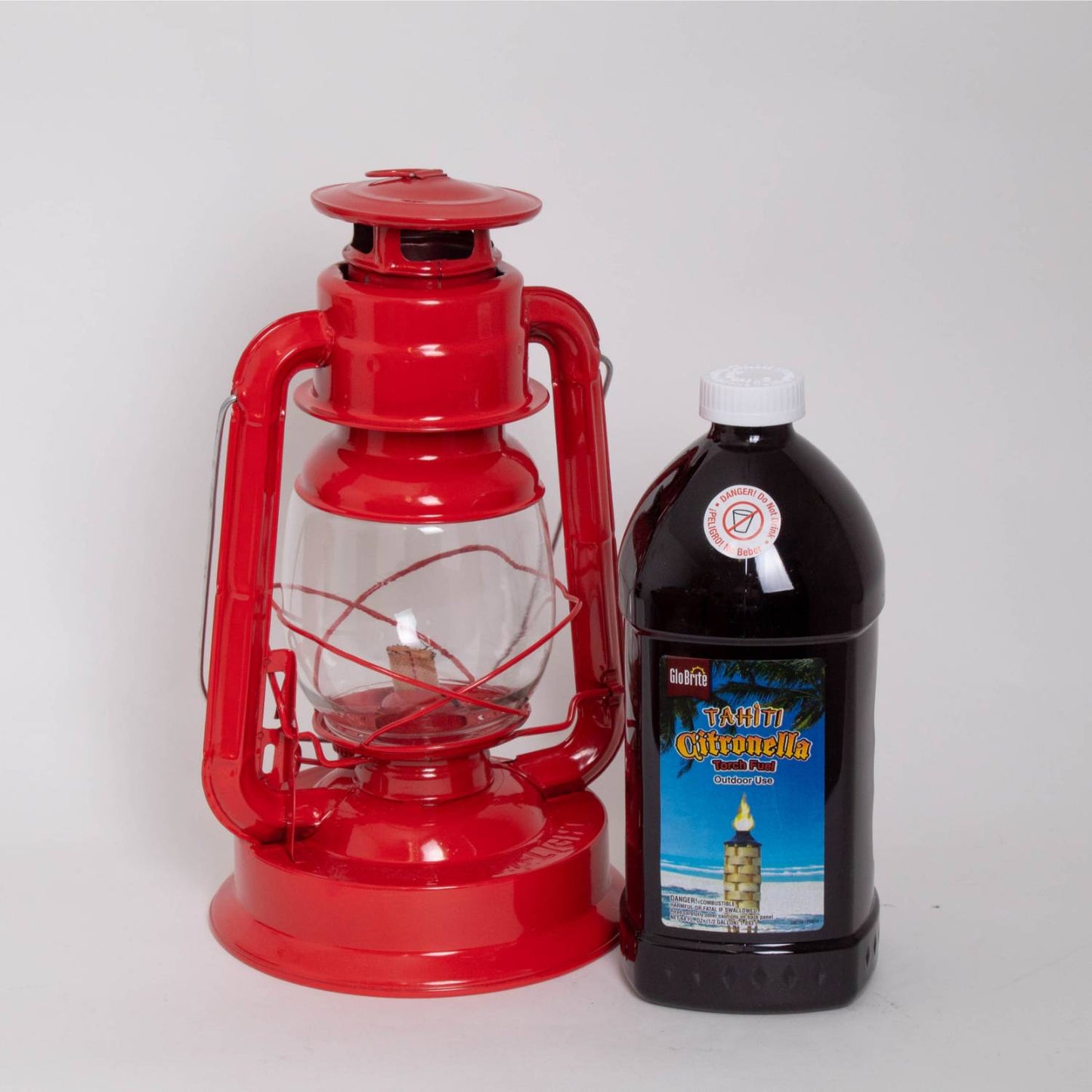 Bright red handcrafted metal oil lantern with clear glass globe and visible wick, next to a black plastic bottle of citronella fuel, suited for Farm, Garden & Tool, Camping, and Pest Control collections.