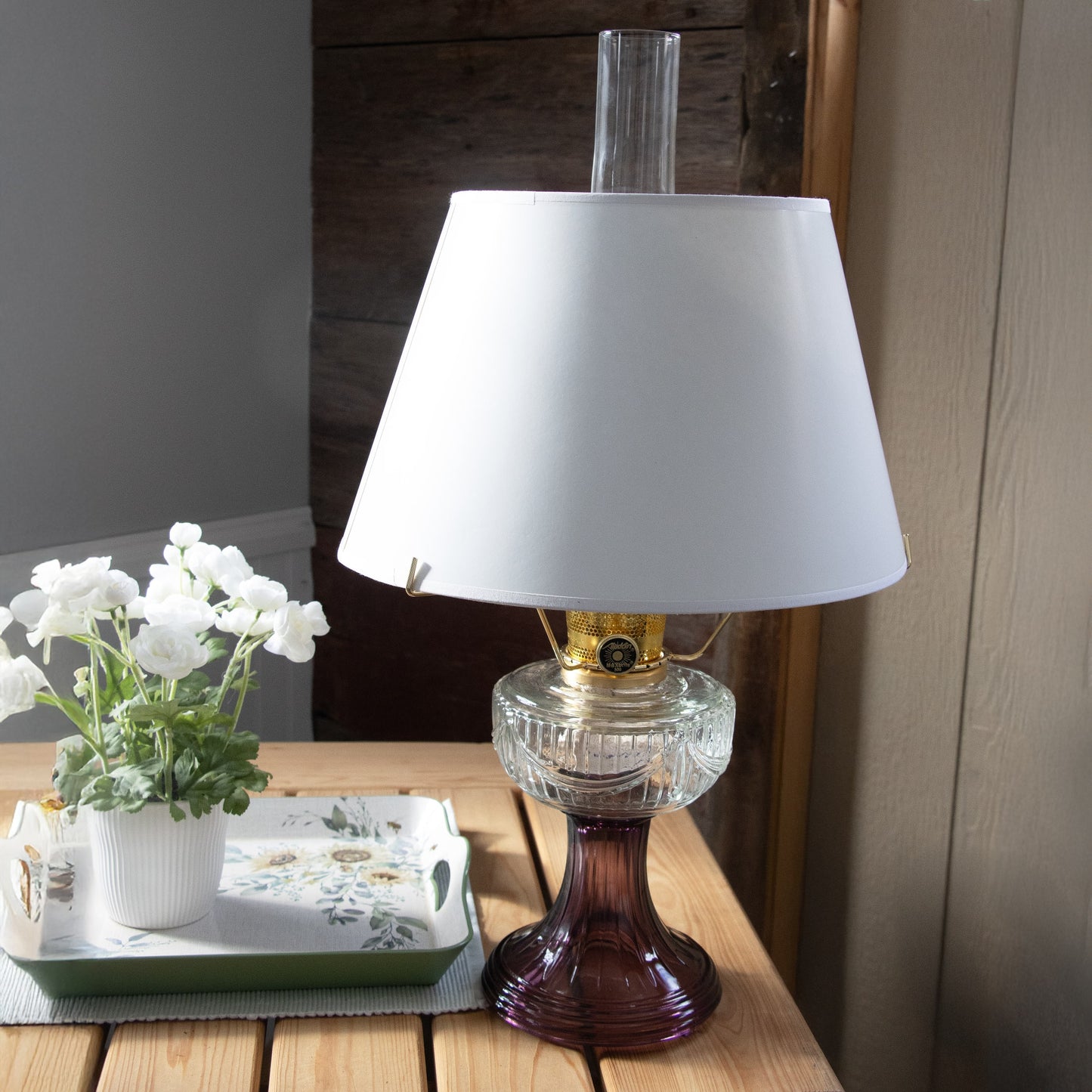 White parchment oil lamp shade with tapered design atop a vintage-style glass oil lamp, displayed on a wooden table next to a potted white flower, fitting Lamps & Lighting and Parts and Accessories collections.